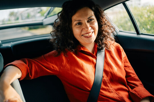 Woman Sitting in the Backseat of a Car With a Smile 