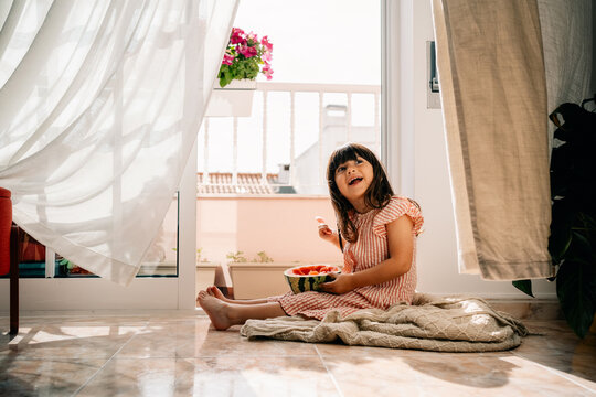 Girl Enjoys Watermelon in a Bright Kitchen During Summer
