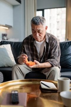 Senior man sorts pills on sofa in modern home