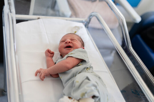 Newborn baby crying feeling initial discomfort in hospital crib
