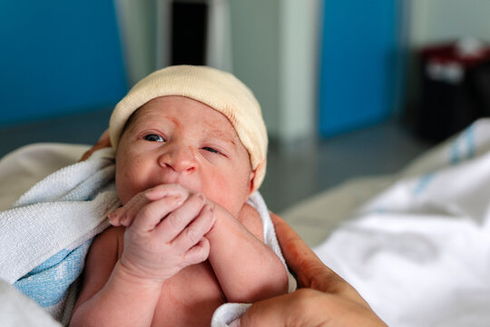 Newborn baby wearing yellow hat in hospital