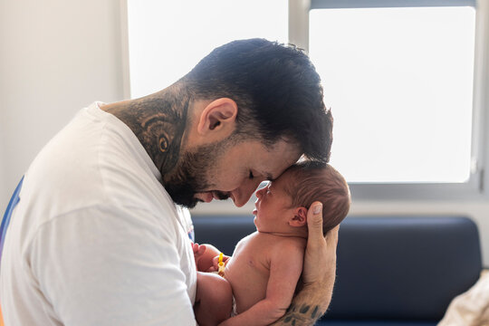 Tattooed father holding newborn baby creating strong bond