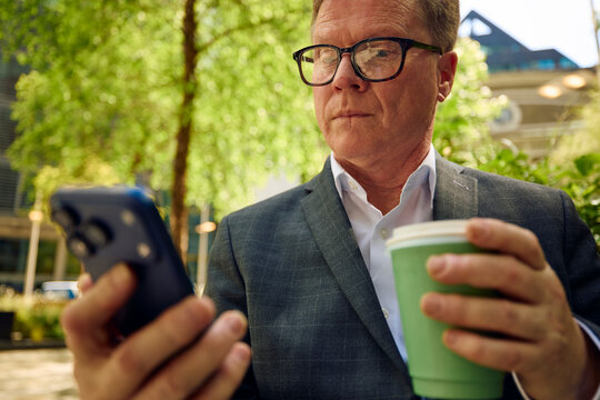Businessman checks his phone outdoors