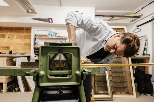 Artisan working wood frame in a studio workshop