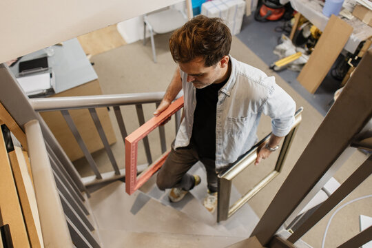Artist carrying art frames walking up stairs in studio