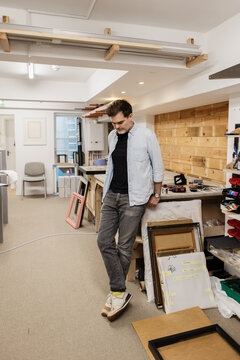 Man framing artwork in busy creative studio workshop