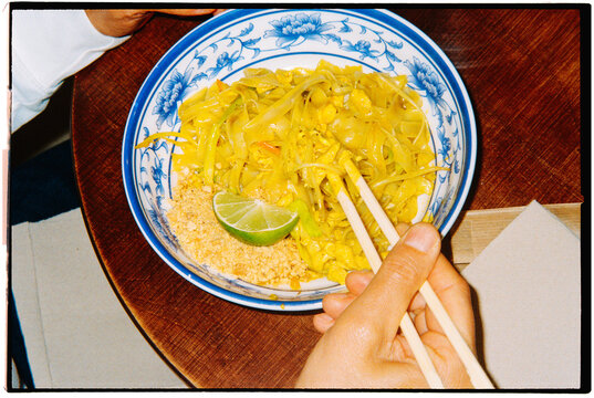 a bowl of pad thai with lime and crushed peanuts, 35mm film