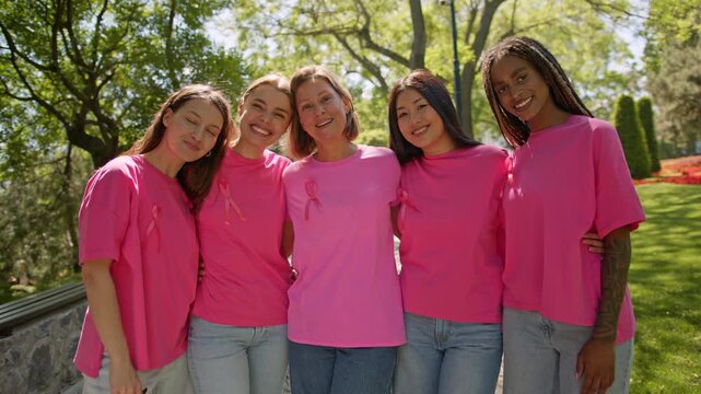 Diverse group of smiling women wearing pink breast cancer awareness ribbons