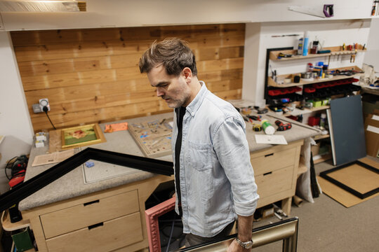 Artist carrying picture frames in workshop