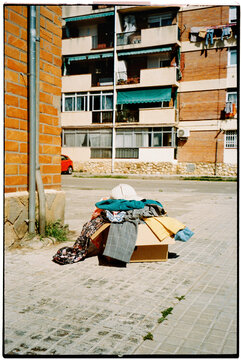 garments spill from a box on a paved sidewalk, 35mm film