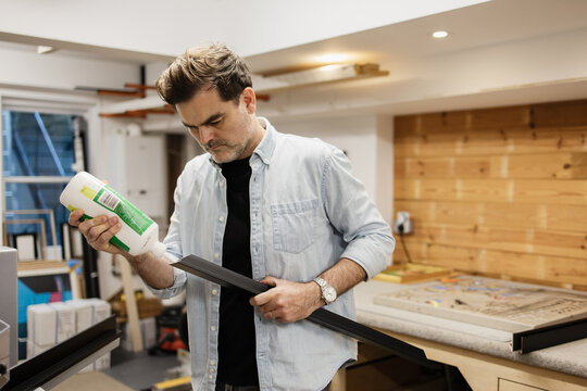 Craftsman applying glue for framing artwork in a studio