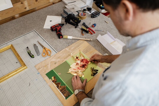 Artist creating collage with gold leaf in workshop studio