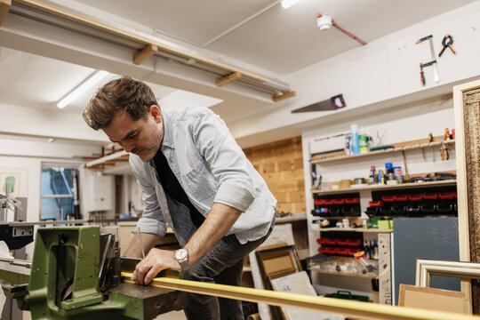 Framer cutting wood for picture frame in workshop