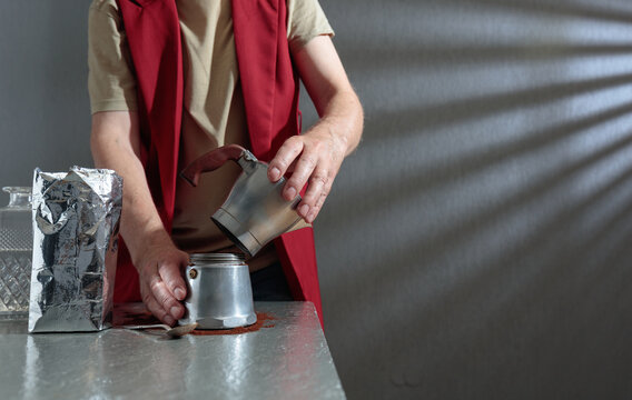 A barista prepares a coffee using a classic Italian moka pot.