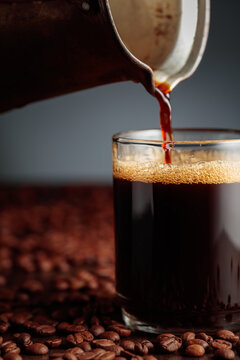 Black coffee is poured into a glass cup.