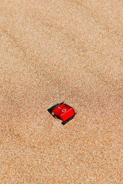 a close-up of a red on/off switch set to on in the sand