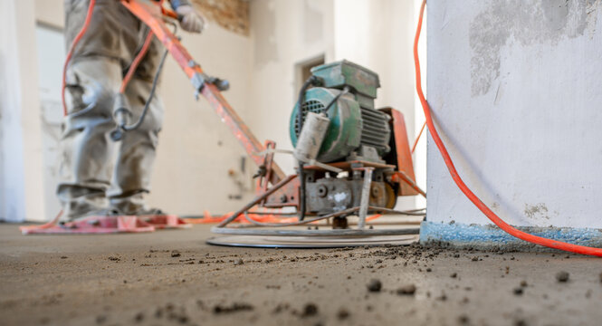 Filling the floor of a renovated apartment with concrete, screed and leveling the floor by construction workers. Even floors made of a mixture of cement, industrial concreting. 
