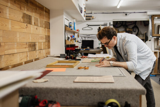 Craftsman working on custom picture frame in art workshop