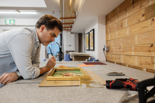 Artist examining artwork in repair workshop