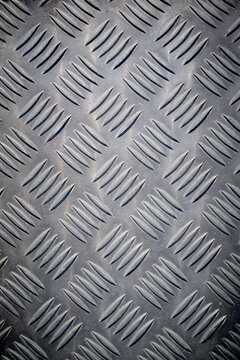 Background created with the foreground texture of a grooved metal surface on a pedestrian crossing to prevent slipping.