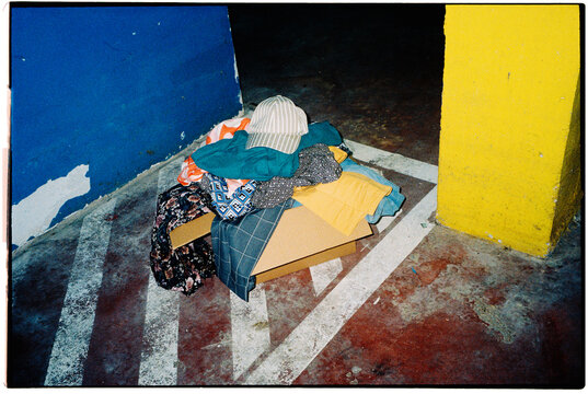 a cardboard box filled with clothes in a parking garage, 35mm film