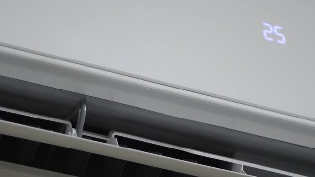 Modern air conditioner unit operating and showing 25 degrees. Concept of HVAC systems, temperature control, and home cooling