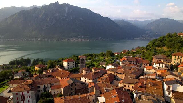 Cinematic Sunset Aerial Drone Pull Back View of Hilltop Borgo Claino con Osteno Lake Lugano Italy Romantic Medieval Village Nestled Above Lake with Dramatic Mountain Backdrop Stunning Golden Hour 4K