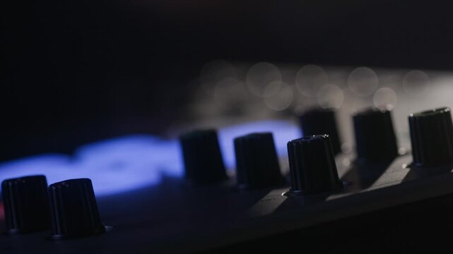 Music studio close up, Close up hands shot of sound engineer using mixing console, remote control for adjusting sound, audio mixer. Musician creates music, makes remix for DJ set. Sound