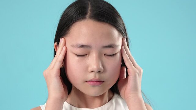 Little girl rubbing temples suffering from headache or stress in the studio