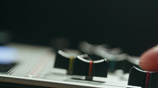 Music studio close up, Close up hands shot of sound engineer using mixing console, remote control for adjusting sound, audio mixer. Musician creates music, makes remix for DJ set. Sound