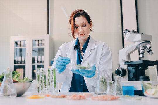 Scientists in lab coats work with plants in a modern lab, focusing on research and experimentation under bright, sterile conditions.