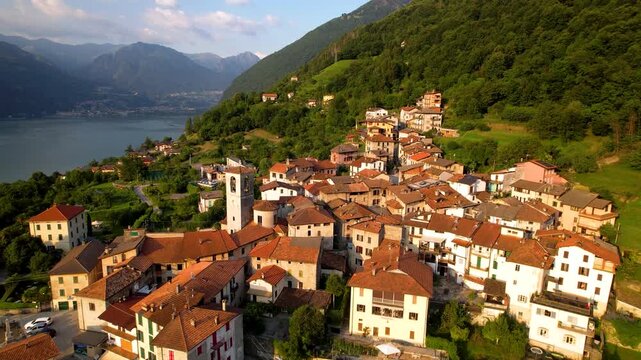 Claino con Osteno Italy Sunset 4K Drone. Pull back aerial flight over beautiful hilltop borgo village by Lake Lugano. Scenic Lombardy region alpine mountain valley landscape b roll video asset