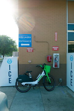 Rental electric scooter parked by gas station ice machine, emergency telephone, shutoff button and fire extinguisher. St Paul Minnesota MN USA