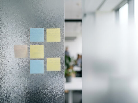 Office glass partition with a cluster of yellow and blue sticky notes attached, fostering a collaborative and productive work environment