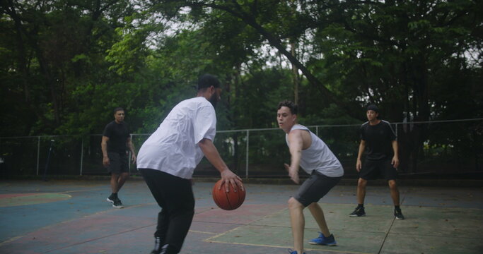 Friends of diverse backgrounds enjoying basketball game on outdoor court in urban area, showing friendship, energy, and teamwork
