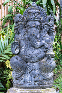 Ancient-style stone statue of Lord Ganesha, the Hindu deity of wisdom, prosperity, and success. Beautifully carved Balinese sculpture displayed in a traditional setting, representing spirituality, cul