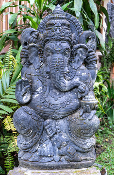 Ancient-style stone statue of Lord Ganesha, the Hindu deity of wisdom, prosperity, and success. Beautifully carved Balinese sculpture displayed in a traditional setting, representing spirituality, cul