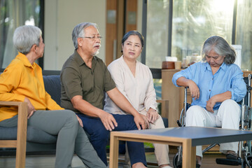Obraz premium Aged care: Senior Asian woman seated in a wheelchair outdoors with her family and a smiling nurse, enjoying a gentle walk through a leafy garden, gentle wellbeing moment