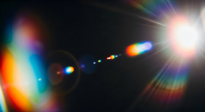 Dramatic lens flare with vibrant rainbow spectrum and bright light burst on black background
