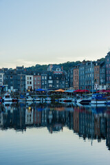 Fototapeta premium Beautiful reflection of traditional slate houses and boats on calm water in the historic harbor of Honfleur, Normandy, France. Picturesque travel background.