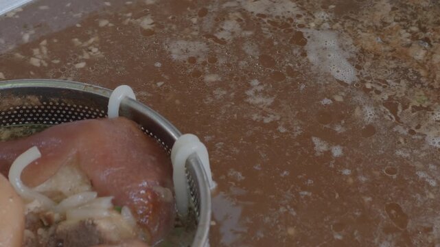 Close-up of Pork Leg and Broth Simmering in a Large Pot at a Street Food Stall