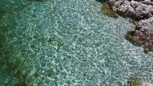 The enchanting view of the crystal-clear turquoise lake and the natural rock formations along the shore. A serene tropical seaside landscape.