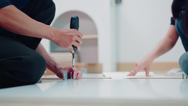 Couple Assembling Flat Pack Furniture Together at Home with Electric Screwdriver