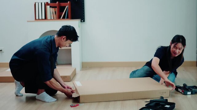 Asian Couple Assembling Flat Pack Furniture Together on Living Room Floor