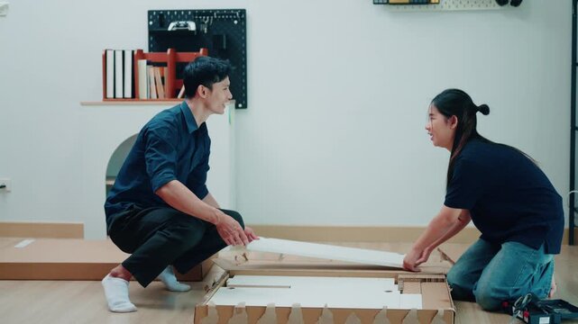 Asian Couple Assembling Flat Pack Furniture Together on Living Room Floor