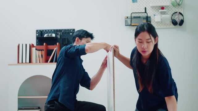 Asian Couple Assembling Flat Pack Furniture Together on Living Room Floor