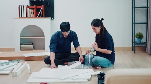 Asian Couple Assembling Flat Pack Furniture Together on Living Room Floor
