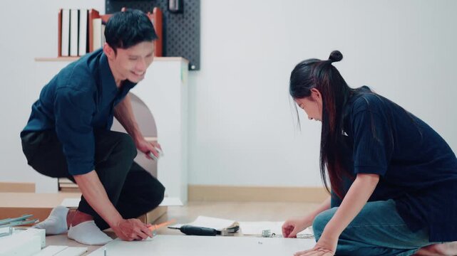Asian Couple Assembling Flat Pack Furniture Together on Living Room Floor