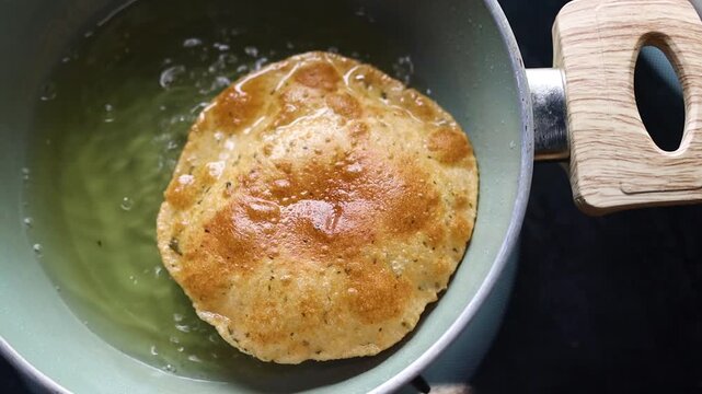 Indian bread or puri or pudi being fried in hot oil