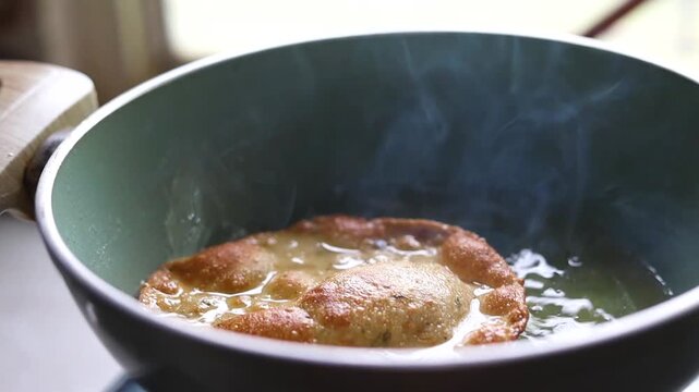 Indian bread or puri or pudi being fried in hot oil